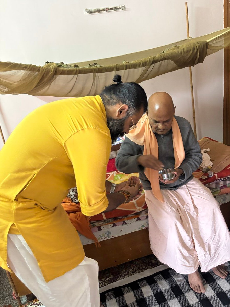 दिव्य मिलन का केंद्रीय क्षण — कबीर जी महाराज (पीले, झुके हुए) पूज्य रामेश्वरानंद गिरि जी (गंजे, बिस्तर पर) से ज़िम्मेदारी स्वीकार करते हुए — नागली आश्रम, पंचकूला